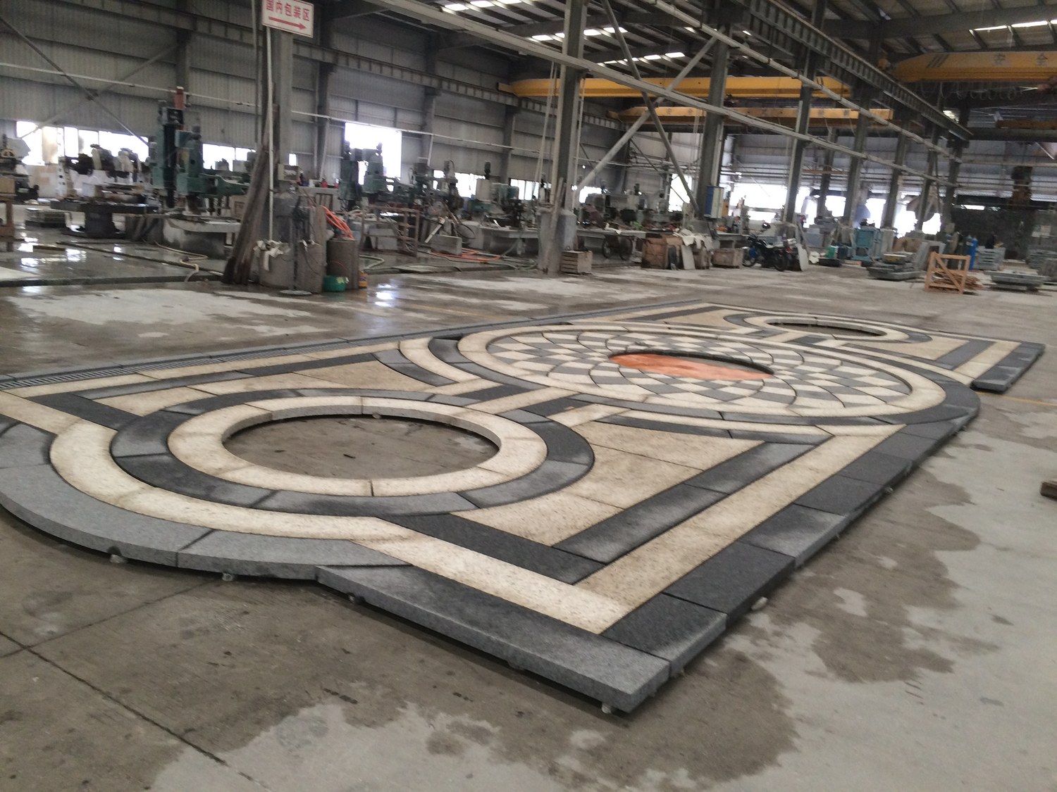 A granite paving medallion in South African Black and Giallo Santa Cecilia, dry-laid complete on the factory floor before packing