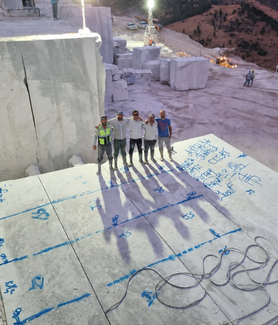 Marble block marked out for cutting at the quarry, with the team standing on the block face at dusk