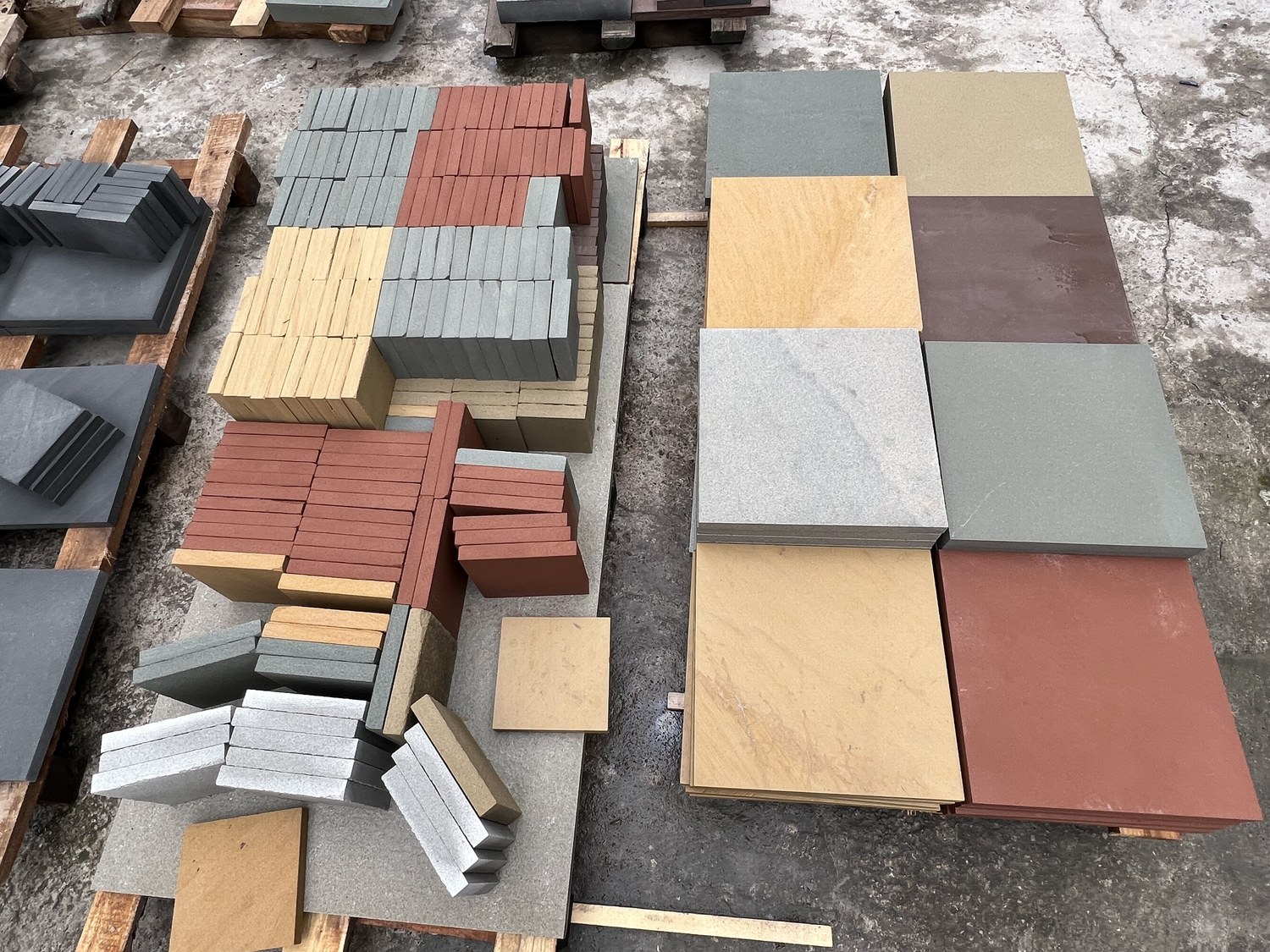 A colour range of sandstone tiles in grey, tan, beige, plum and red laid out for comparison