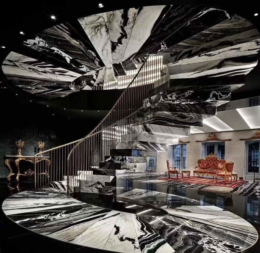 A spiral staircase, ceiling and floor cut from the same black-veined marble family and book-matched across every surface