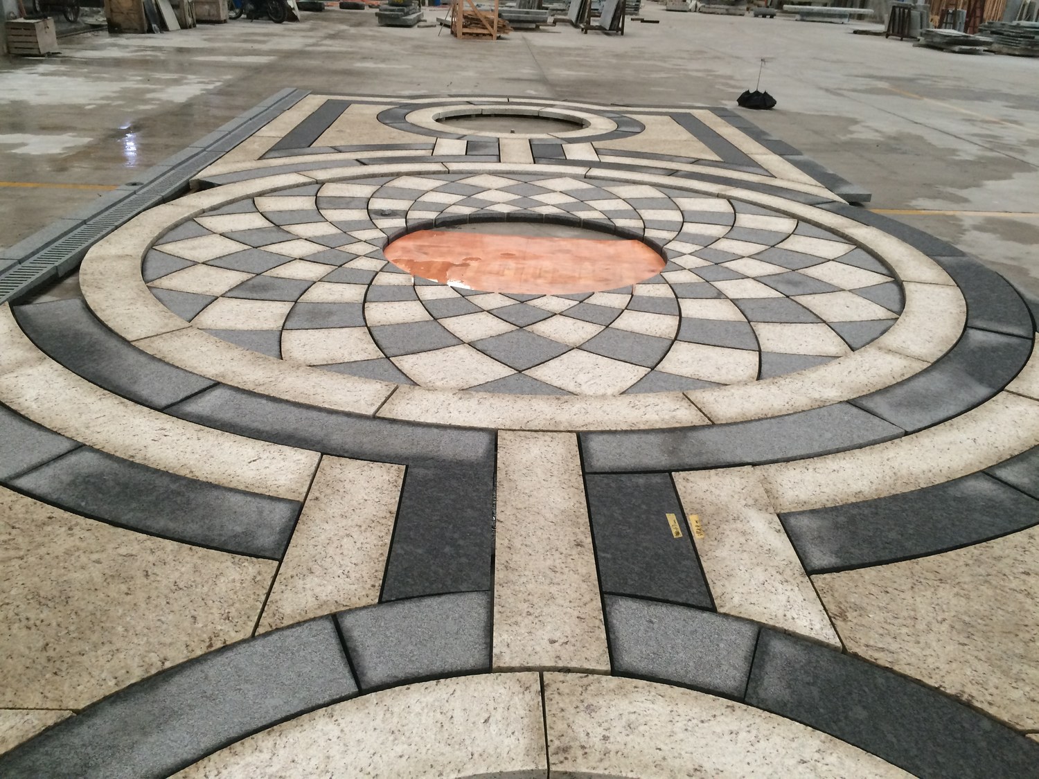 A close view of a radiating fan-pattern granite medallion in cream and dark grey stone