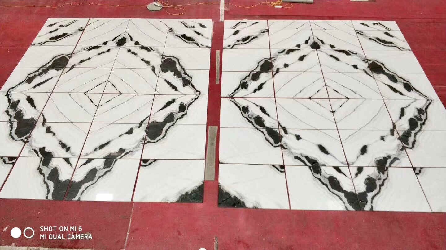 A four-way quarter book-match of black-veined marble tiles, veining radiating outward from a centre point in a diamond pattern