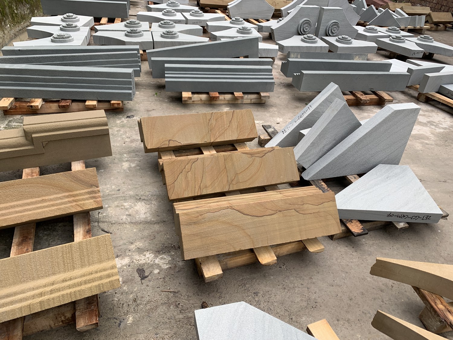 Sandstone architectural mouldings and carved floral medallions laid out in a yard