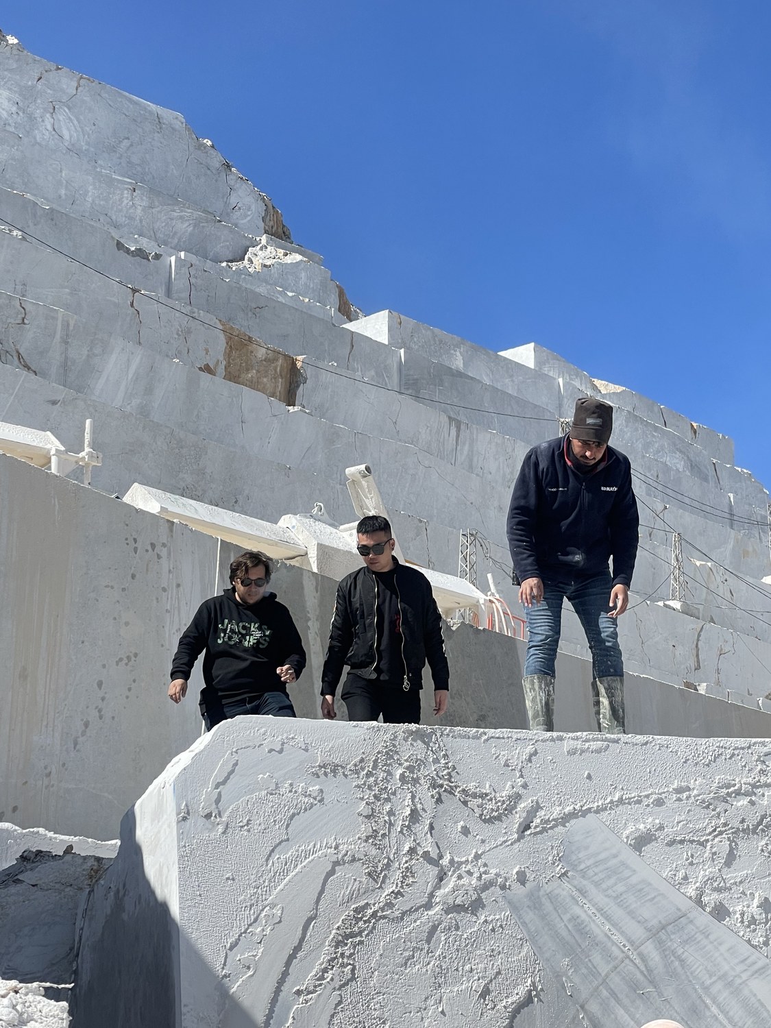 Team standing at a marble quarry inspecting a freshly cut block face
