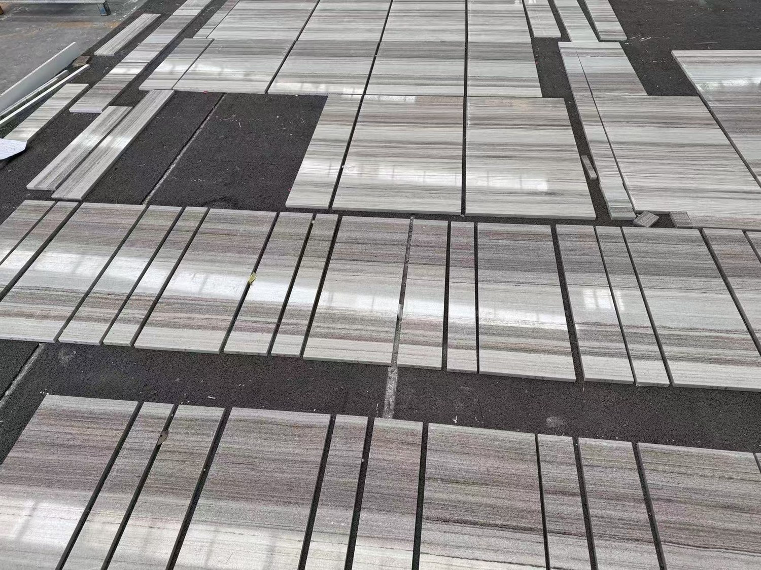 A ground-level view of polished Silver Travertine slabs reflecting overhead light