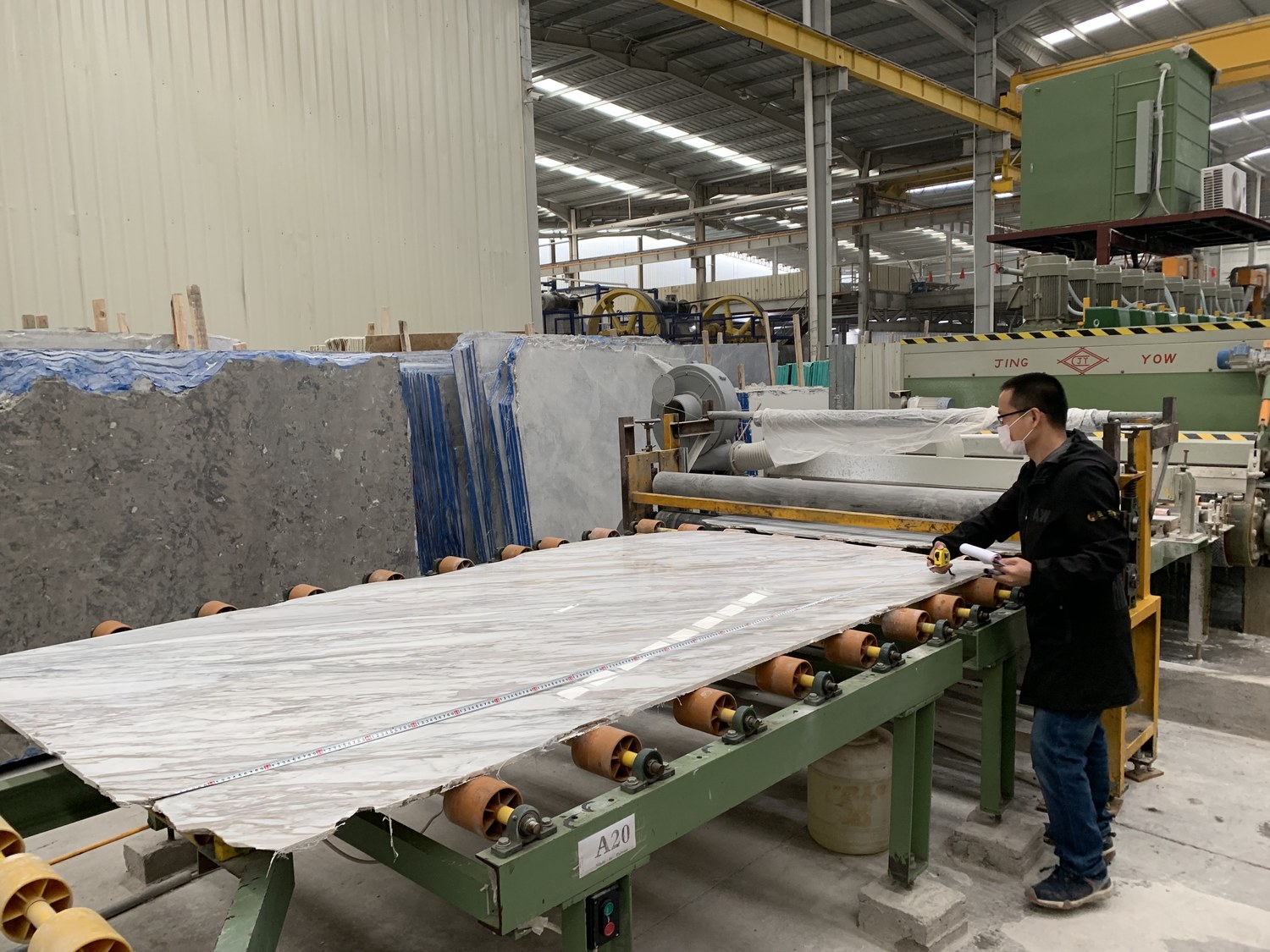 A worker measures a marble slab on the production line inside a stone factory