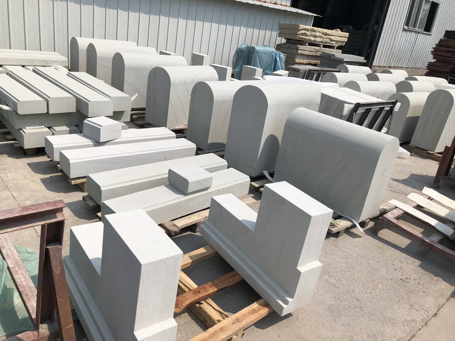 Finished arched sandstone coping and kerb sections staged in a yard