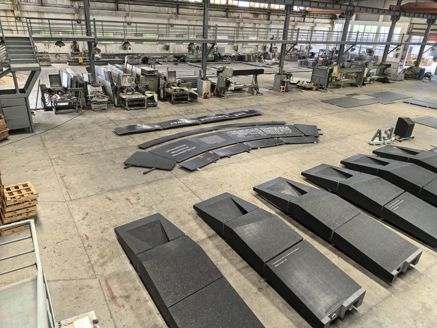 Angular granite memorial bench forms carved with community quotes, alongside individually cut dimensional letters