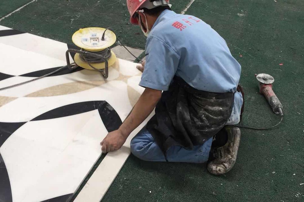 A black and white marble medallion being assembled piece by piece in the factory