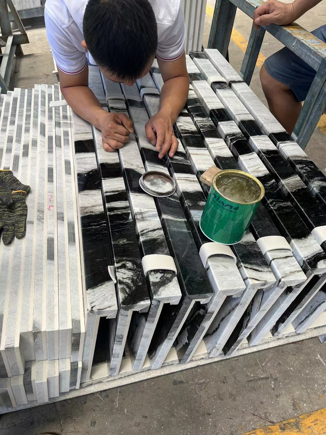 A worker hand-fitting and bonding mitred corner joints on marble skirting pieces
