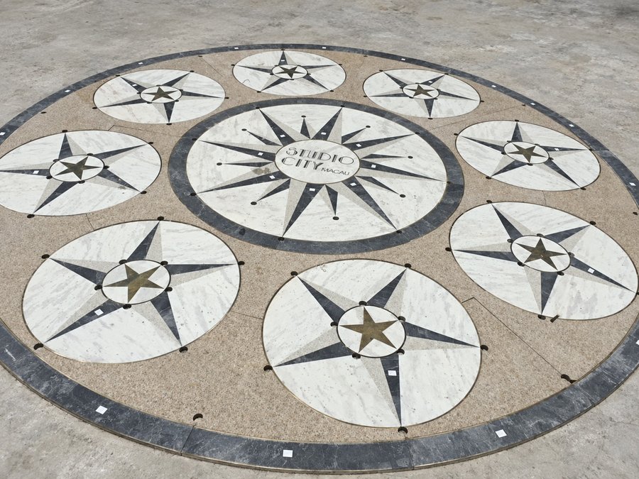 A ten-medallion waterjet compass floor for Studio City, Macau, in marble and dark stone with brass inlay