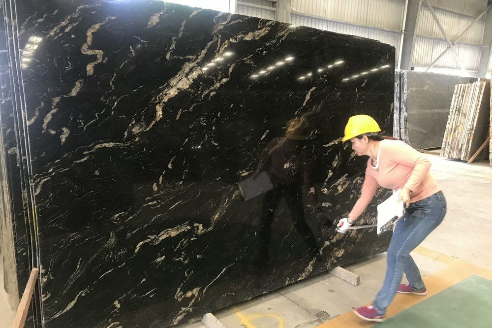 Cosmic Black granite slab being measured and recorded during inspection