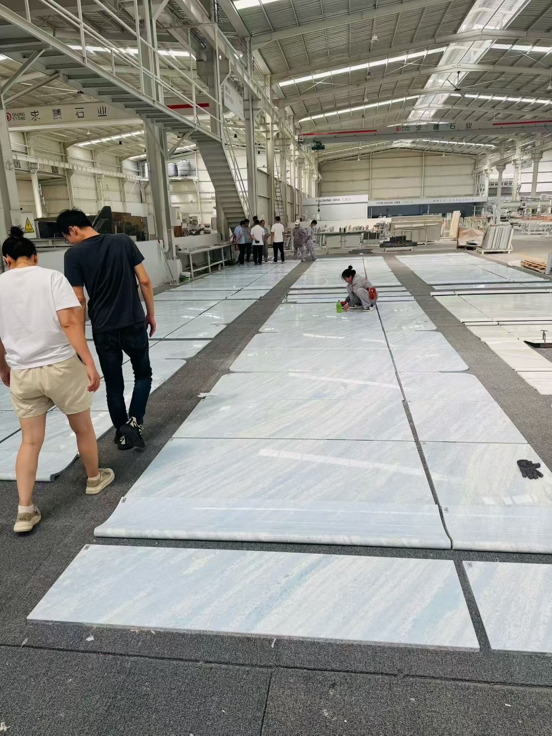 Inspector checking polished stone panels laid out in the factory polishing area