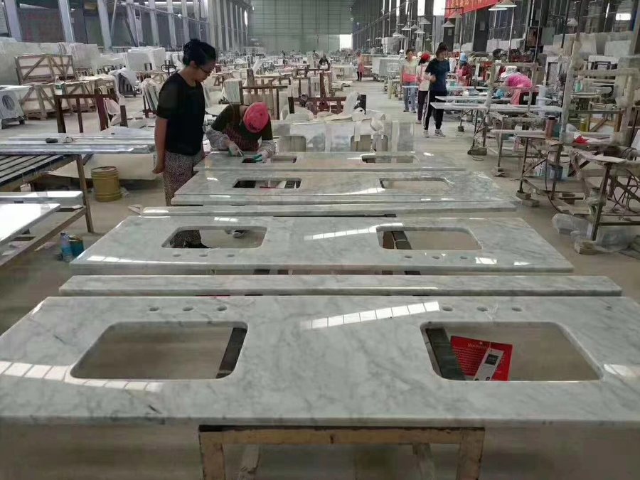 Carrara white marble vanity tops with sink cutouts being finished and inspected