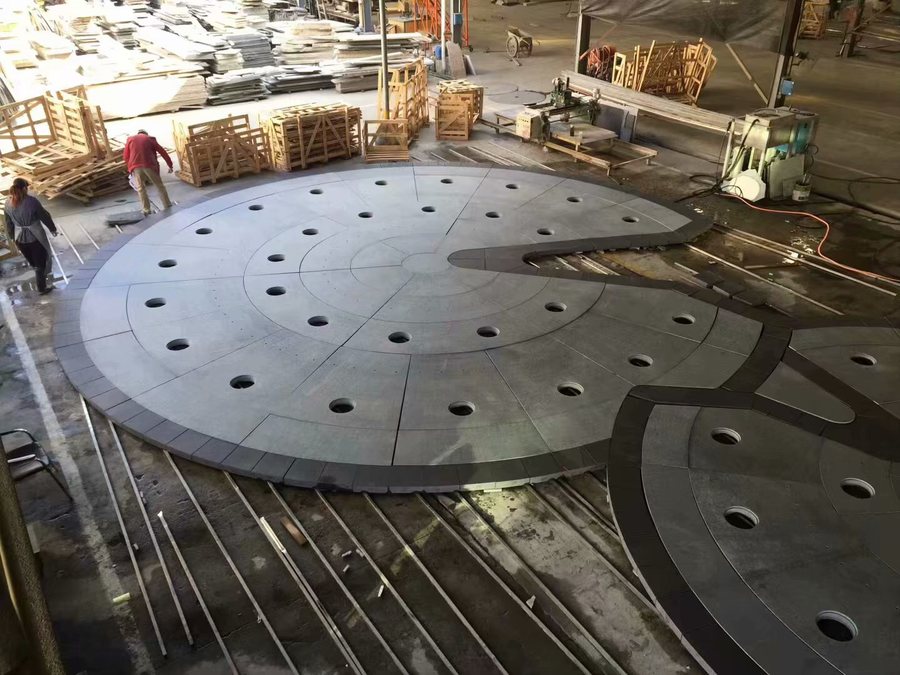 A circular granite water feature dry-assembled in the factory before dismantling and packing