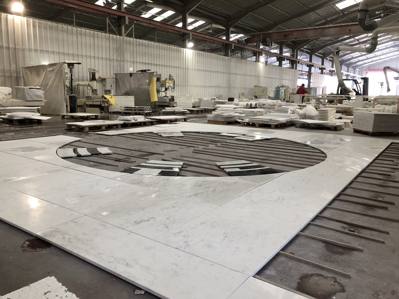 Jazz White marble floor with a waterjet-cut circular medallion dry-fitted on rails inside the factory